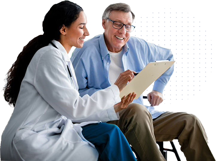 A smiling female doctor is sitting next to an older male patient, showing him information on a clipboard